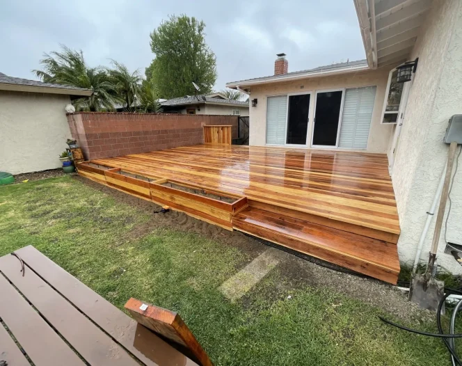 A newly installed wooden deck with two steps and planters